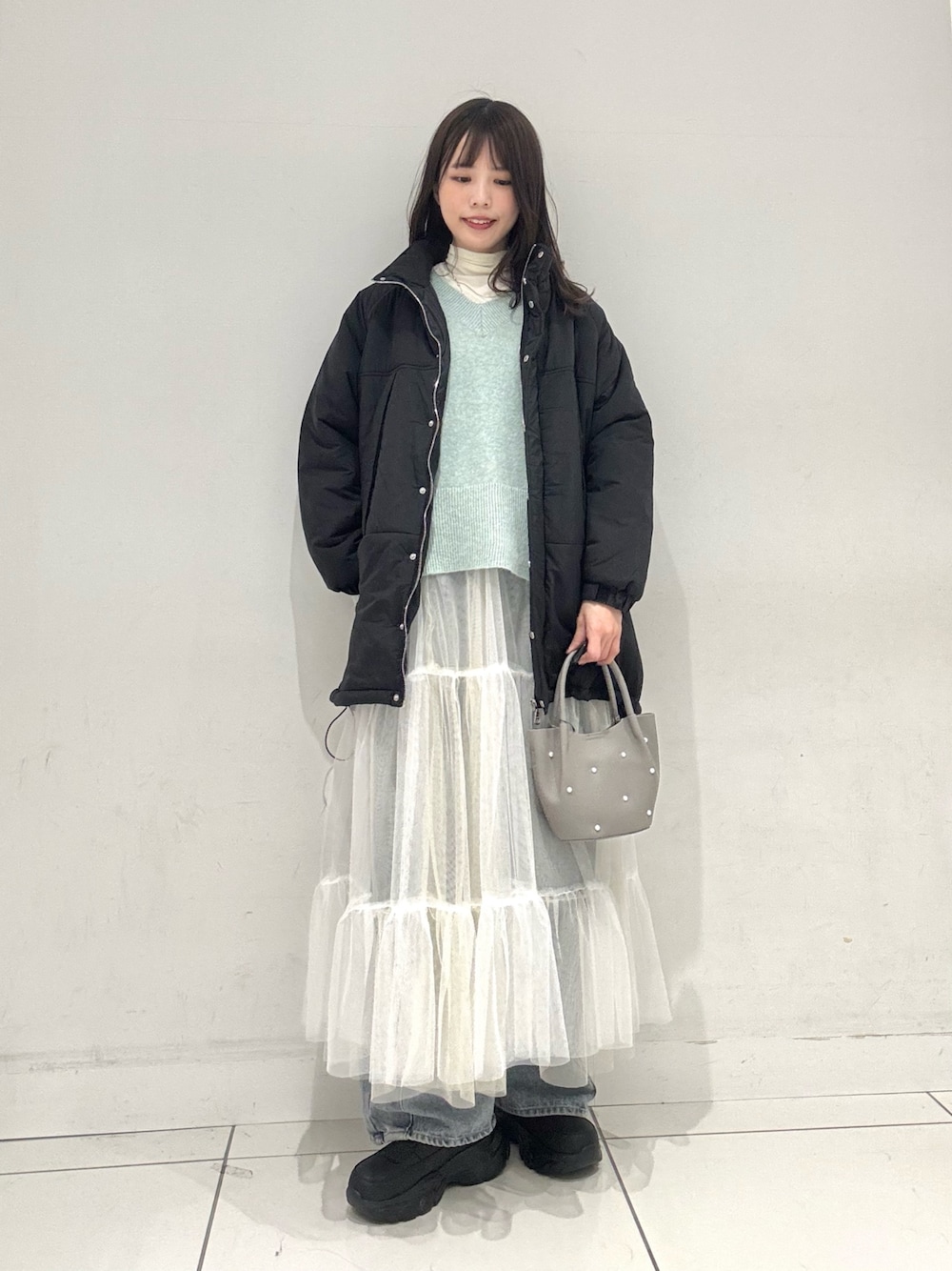 ホワイト系のTシャツ/カットソー、グリーン系のニット/セーター、ホワイト系のスカートを着用したレディースの冬コーディネートの1枚目の写真