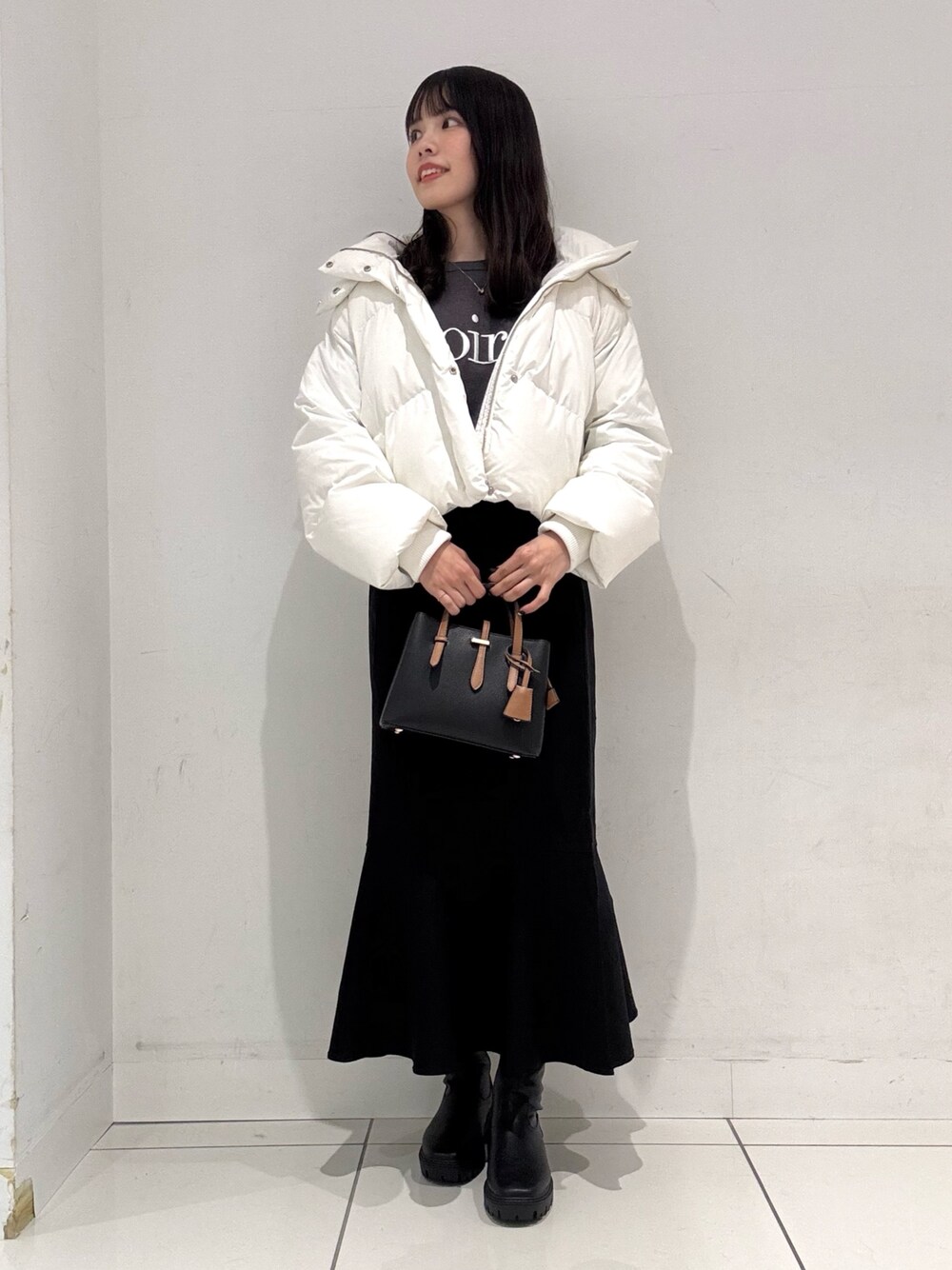 グレー系のニット/セーター、ホワイト系のダウンジャケット/コート、ブラック系のハンドバッグを着用したレディースの冬コーディネートの1枚目の写真
