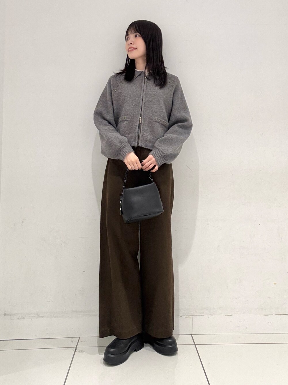 グレー系のカーディガン/ボレロ、ホワイト系のTシャツ/カットソー、ブラック系のショルダーバッグを着用したレディースの冬コーディネートの1枚目の写真