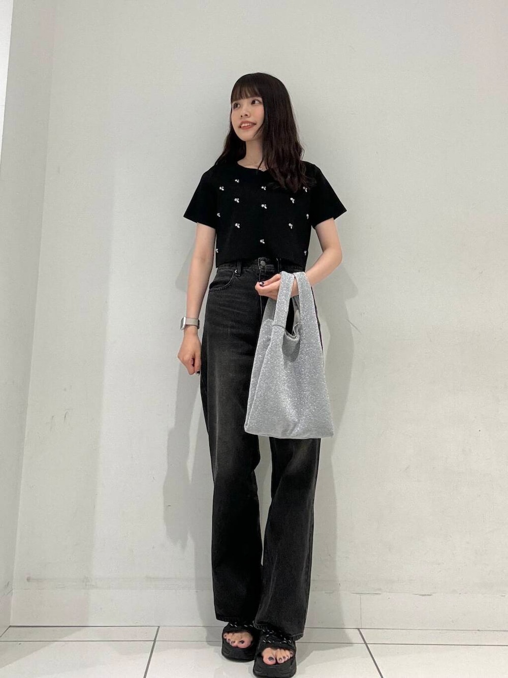 ブラック系のニット/セーター、シルバー系のトートバッグ、ブラック系のデニムパンツを着用したレディースの夏コーディネートの1枚目の写真