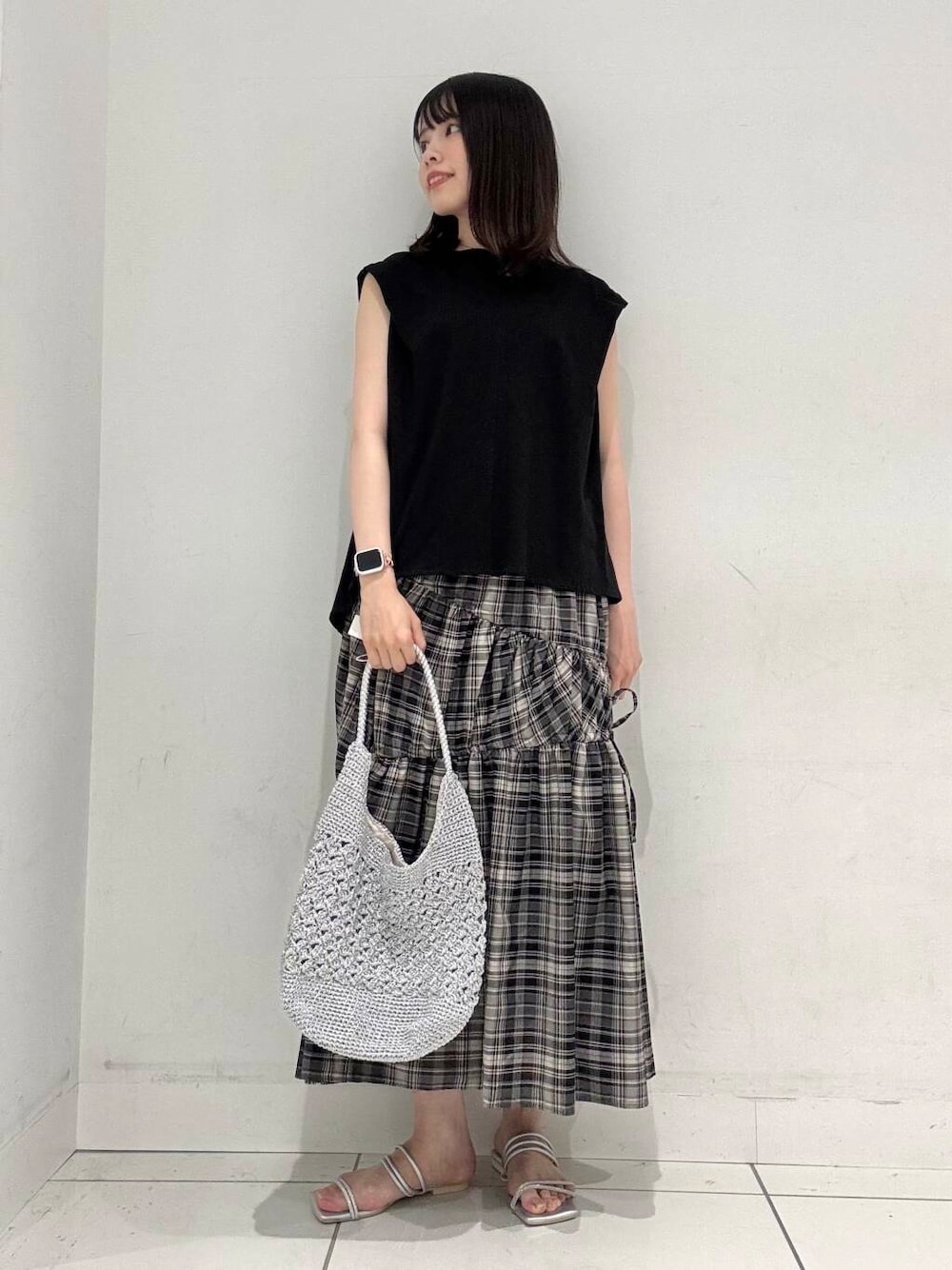 シルバー系のハンドバッグ、シルバー系のサンダル、ブラック系のTシャツ/カットソーを着用したレディースの夏コーディネートの1枚目の写真