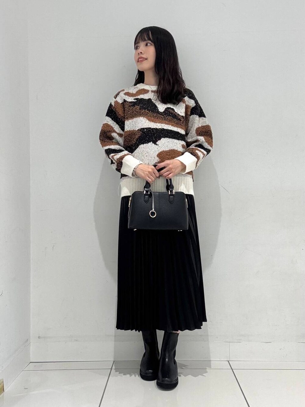 ホワイト系のニット/セーター、ブラック系のブーツ、ブラック系のハンドバッグを着用したレディースの冬コーディネートの1枚目の写真