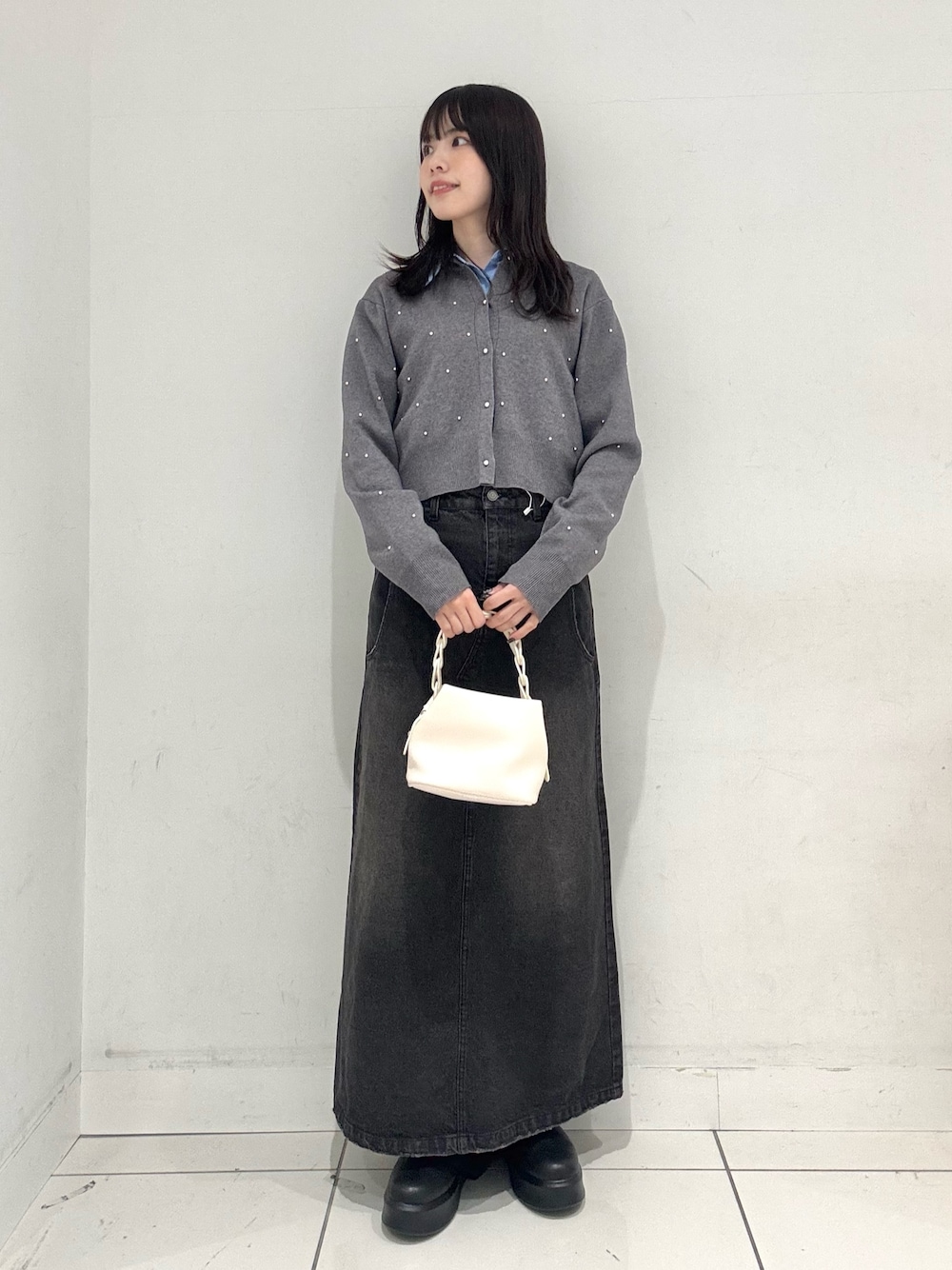 ブラック系のスカート、ブラック系のその他シューズ、ホワイト系のショルダーバッグを着用したレディースの冬コーディネートの1枚目の写真