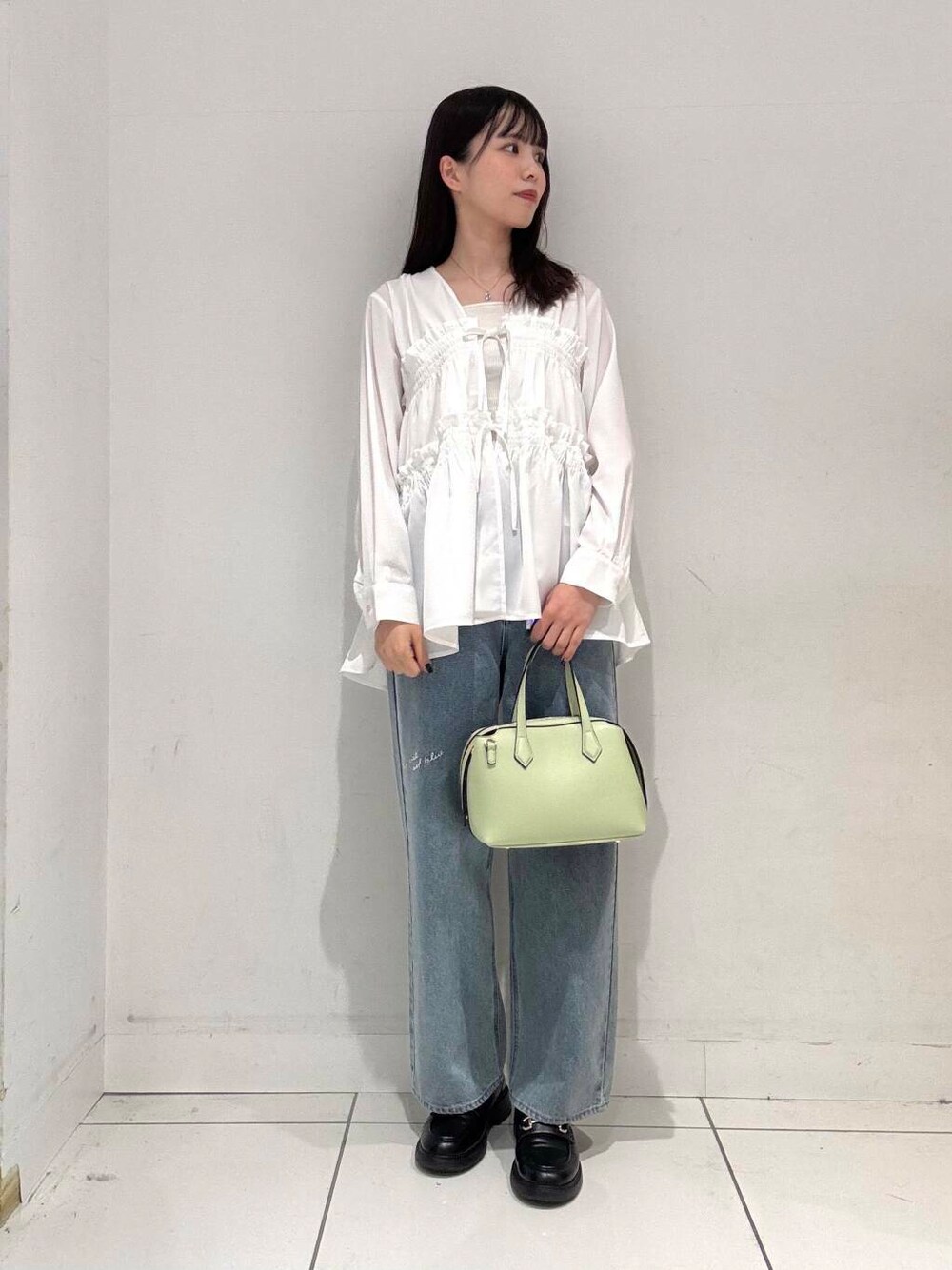 グリーン系のトートバッグ、ブルー系のデニムパンツ、ホワイト系のシャツ/ブラウスを着用したレディースの春コーディネートの1枚目の写真