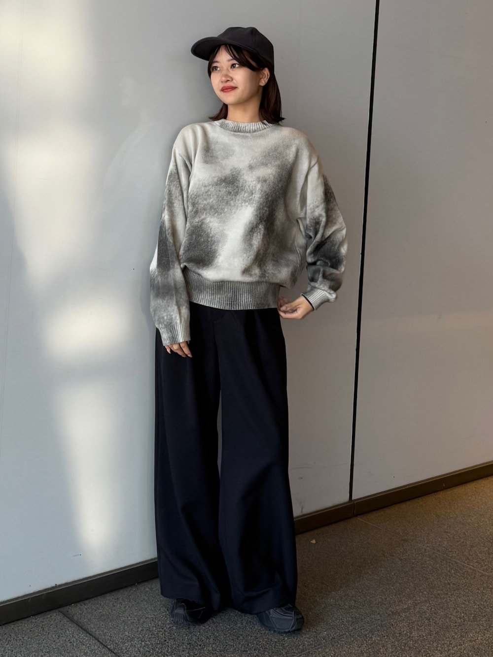 ホワイト系のニット/セーター、ブラック系のスラックスを着用したレディースの冬コーディネートの1枚目の写真