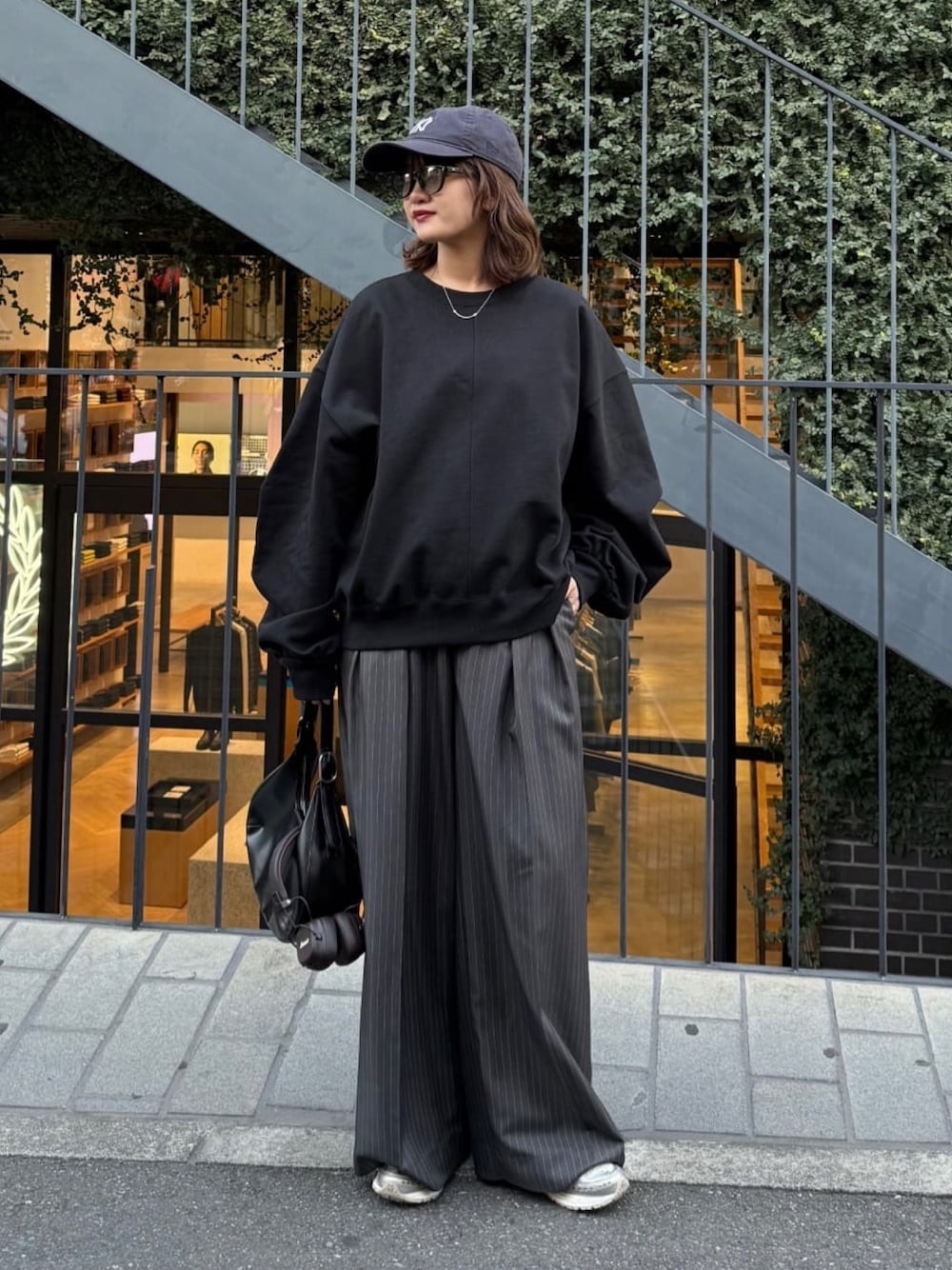 ホワイト系のスウェット、グレー系のスラックス、ブラック系のハンドバッグを着用したレディースの冬コーディネートの1枚目の写真