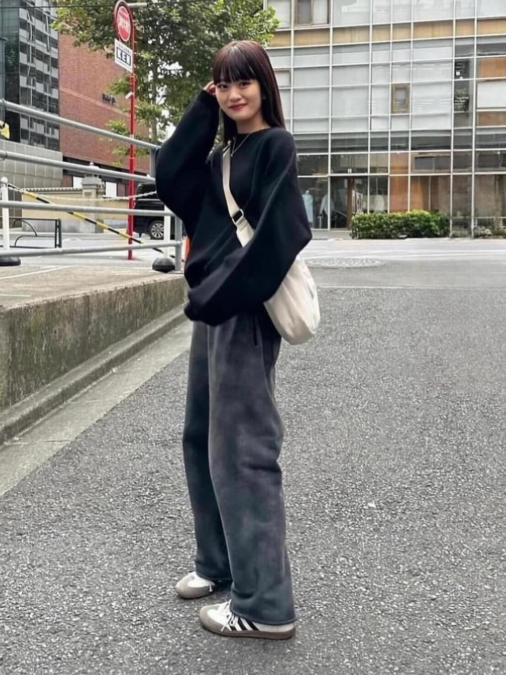 ブラック系のニット/セーター、グレー系のショルダーバッグ、ブラック系のスニーカーを着用したレディースの秋コーディネートの1枚目の写真