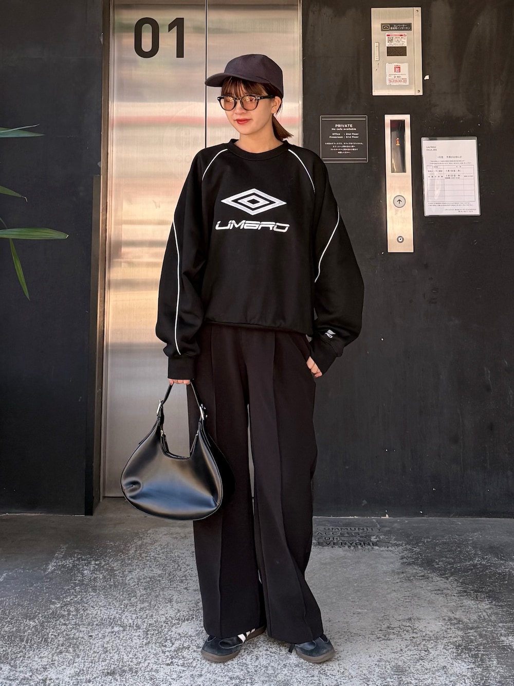 ブルー系のスウェット、ブラック系のハンドバッグ、ブラック系のサングラスを着用したレディースの冬コーディネートの1枚目の写真