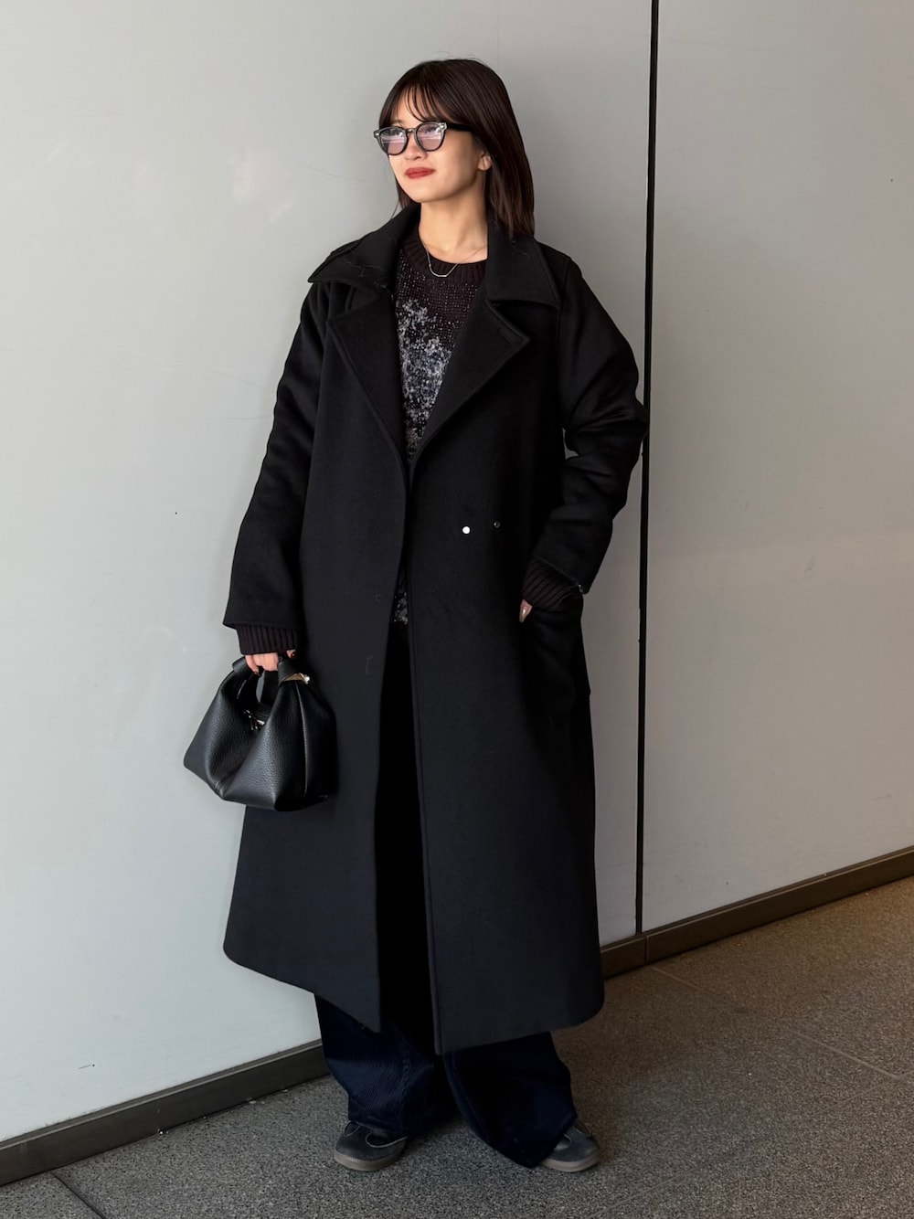 ブラック系のチェスターコート、ブラック系のニット/セーター、ブラック系のトートバッグを着用したレディースの秋コーディネートの1枚目の写真