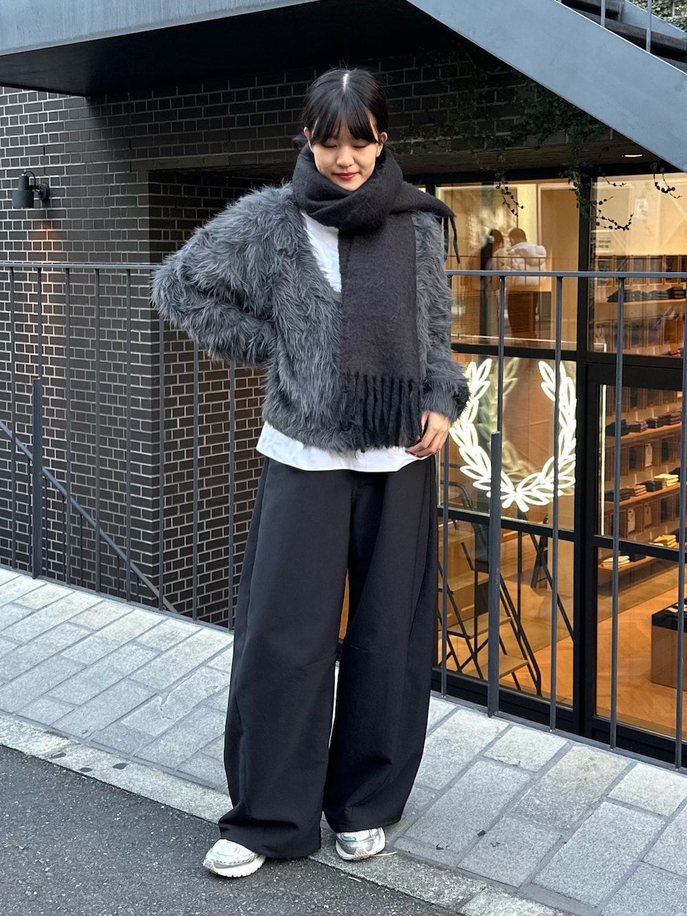 グレー系のカーディガン/ボレロ、ブラック系のスラックス、ホワイト系のスニーカーを着用したレディースの秋コーディネートの1枚目の写真