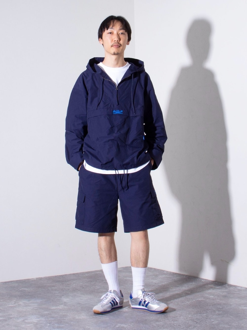 「スポーツミックス、春コーデ、ストリート、春服みてみて、セットアップ、レイヤードスタイル、お出かけコーデ、スニーカー、春アウター、アウトドアスタイル、大人カジュアル、アノラックパーカー、ショートパンツ、春のおしゃ見えテクニック、休日コーデ」｜「JACK PURCELLの【CONVERSE JACK PURCELL/コンバース ジャックパーセル】ナイロンアノラックパーカー ロゴ刺繍（ナイロンジャケット、ブルー系）」を使った、須山さん（メンズ・177cm）の春コーディネートの1枚目の写真
