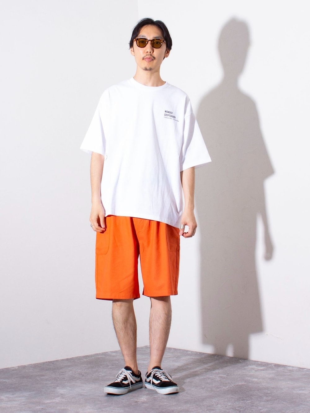 「ロゴT、メガネ男子、カーゴパンツ、デートコーデ、スニーカー、夏コーデ、サングラス、ハーフパンツ、休日スタイル、大人カジュアル、Tシャツ、白Tシャツ、オレンジ、ビッグシルエット、ストリート」｜「GLOSTERの【GLOSTER/グロスター】ウェリントン セルフレーム カラーレンズ サングラス（サングラス、ブラウン系）」を使った、須山さん（メンズ・177cm）の夏コーディネートの1枚目の写真