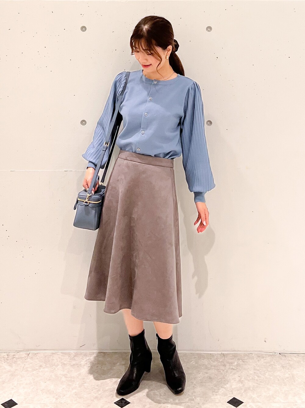 ブルー系のカーディガン/ボレロ、ブルー系のショルダーバッグ、グレー系のスカートを着用したレディースの秋コーディネートの1枚目の写真
