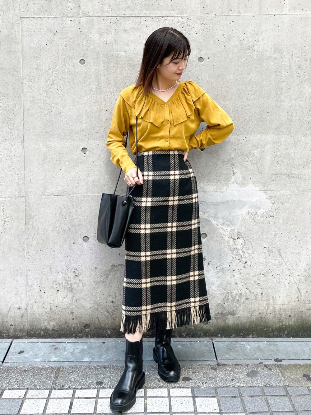 イエロー系のカーディガン/ボレロ、ブラック系のスカート、ブラック系のショルダーバッグを着用したレディースの秋コーディネートの1枚目の写真