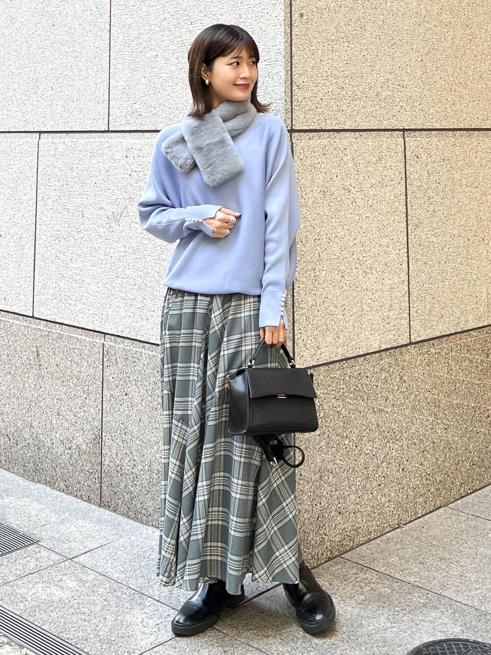 ブルー系のニット/セーター、ブラック系のショルダーバッグ、グレー系のスカートを着用したレディースの冬コーディネートの1枚目の写真