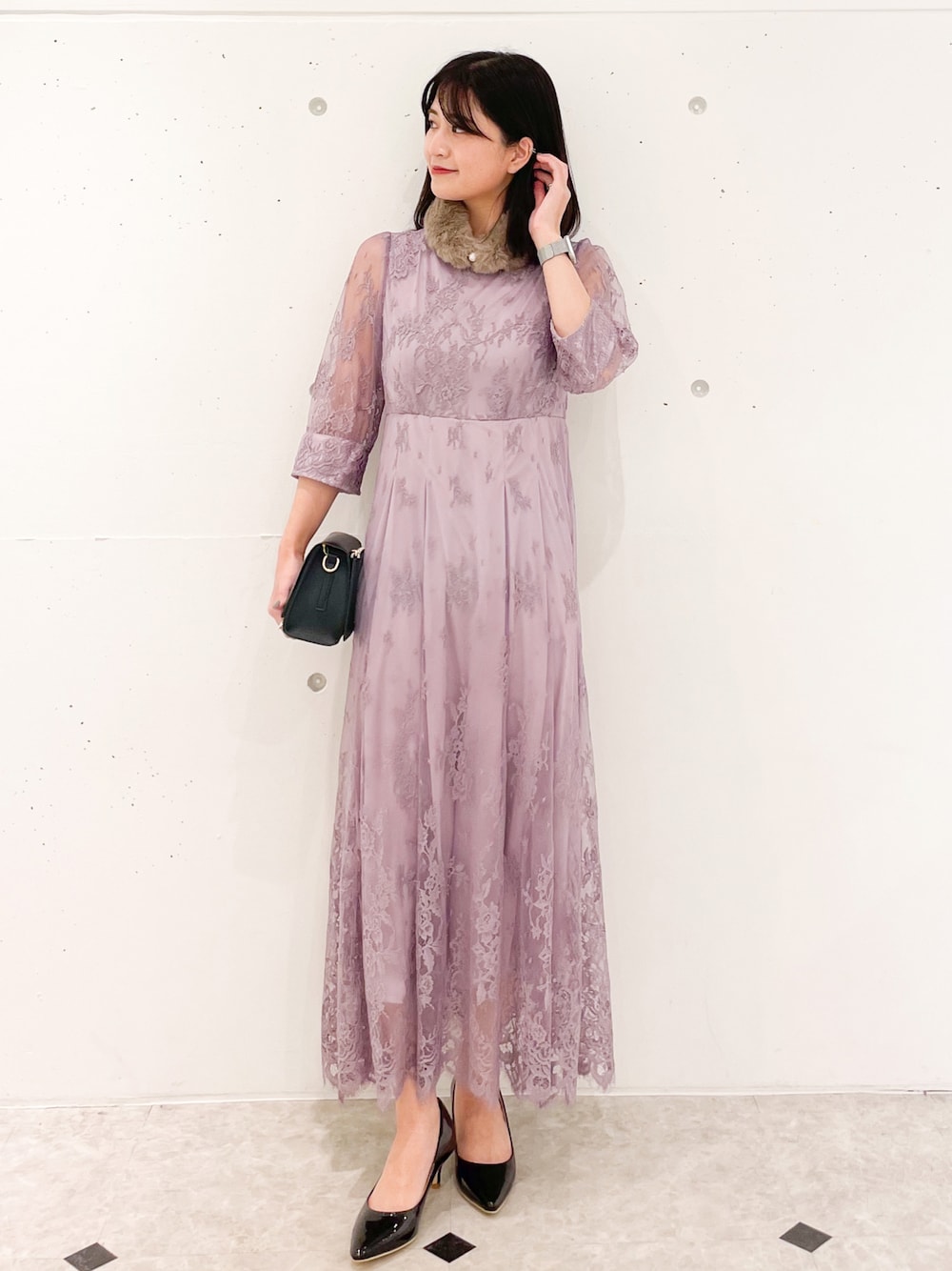 ピンク系のドレス、ブラック系のショルダーバッグ、ブラック系のパンプスを着用したレディースの冬コーディネートの1枚目の写真