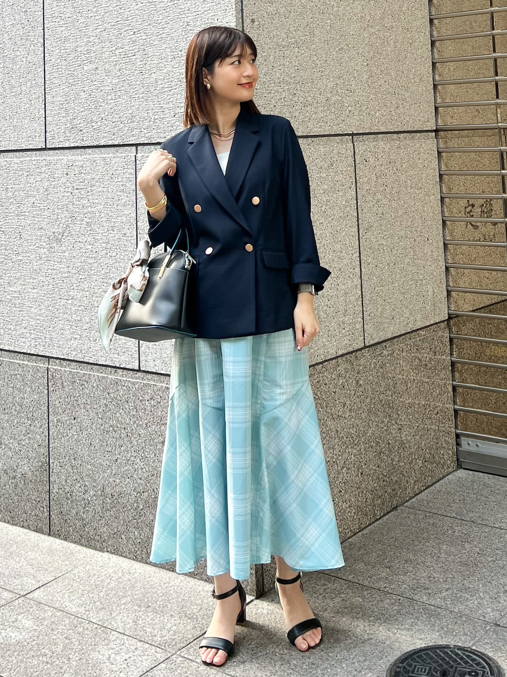 ブルー系のテーラードジャケット、ブラック系のショルダーバッグ、ブルー系のスカートを着用したレディースの春コーディネートの1枚目の写真