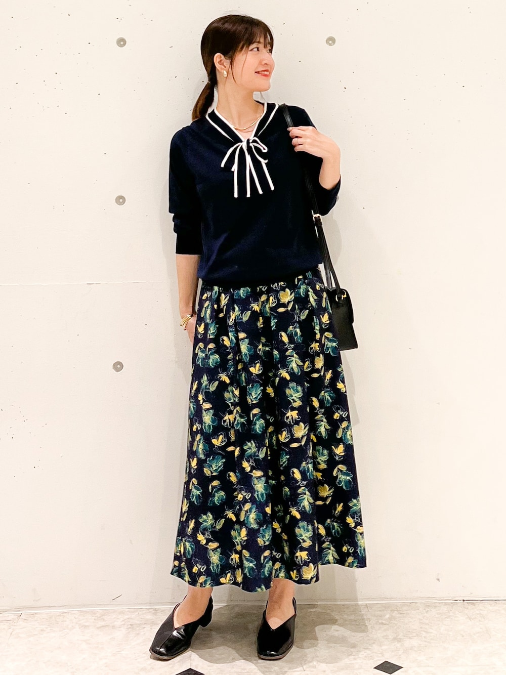 ブルー系のカーディガン/ボレロ、ブルー系のスカート、ブラック系のショルダーバッグを着用したレディースの春コーディネートの1枚目の写真