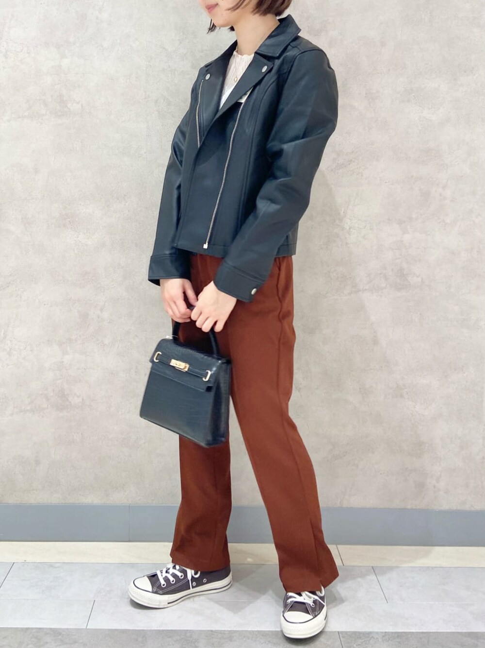 ブラック系のブルゾン、ブラック系のショルダーバッグ、ブラウン系のスラックスを着用したレディースの秋コーディネートの1枚目の写真