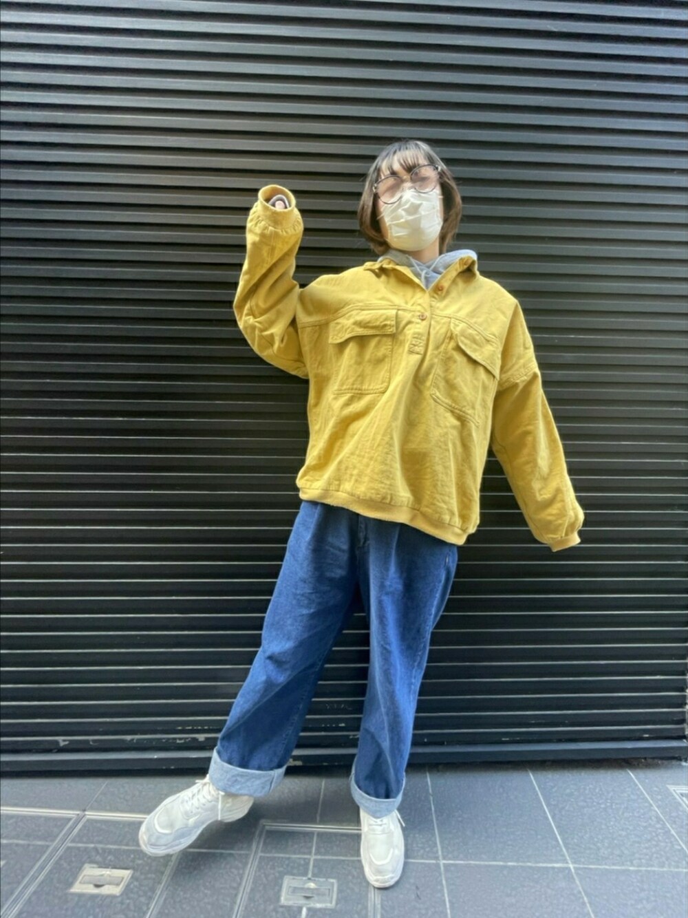 イエロー系のトップス、ブルー系のデニムパンツ、グレー系のパーカーを着用したレディースの春コーディネートの1枚目の写真