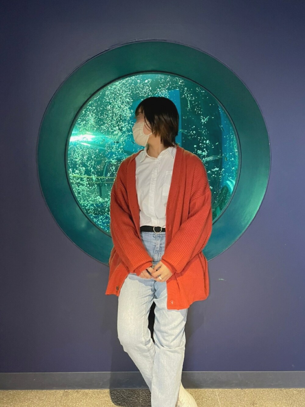 ブルー系のデニムパンツ、オレンジ系のカーディガン/ボレロ、ホワイト系のシャツ/ブラウスを着用したレディースの春コーディネートの1枚目の写真