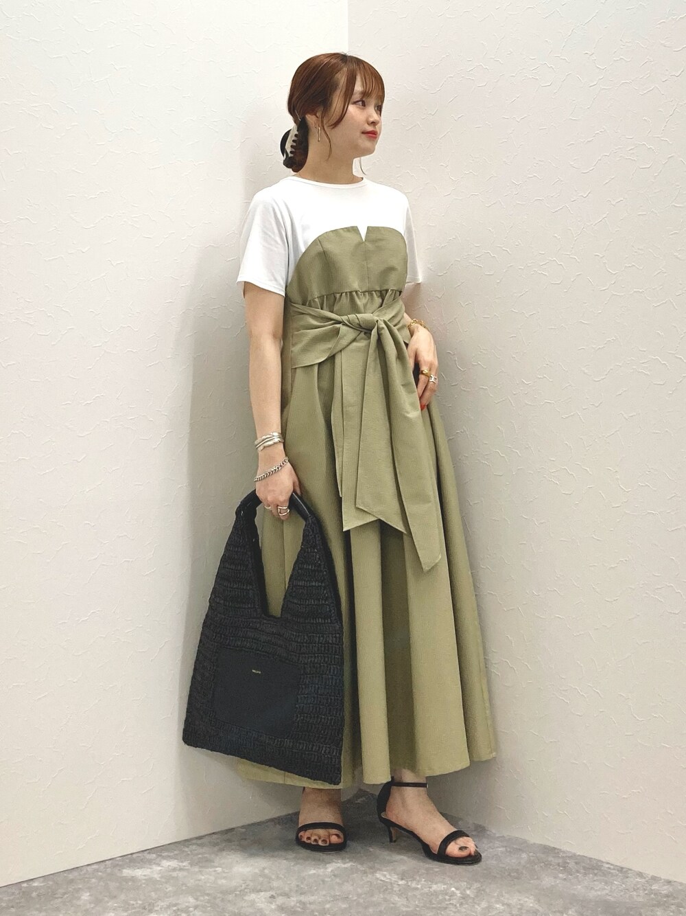 グリーン系のワンピース、ブラック系のサンダル、ブラック系のかごバッグを着用したレディースの春コーディネートの1枚目の写真