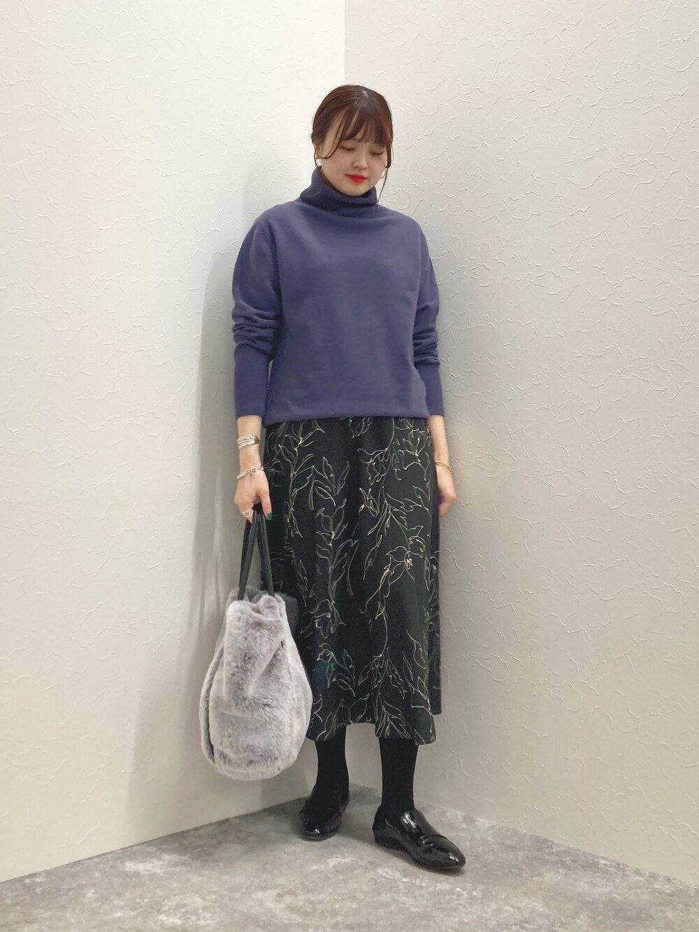 グレー系のニット/セーター、ブラック系のスカート、グレー系のトートバッグを着用したレディースの冬コーディネートの1枚目の写真