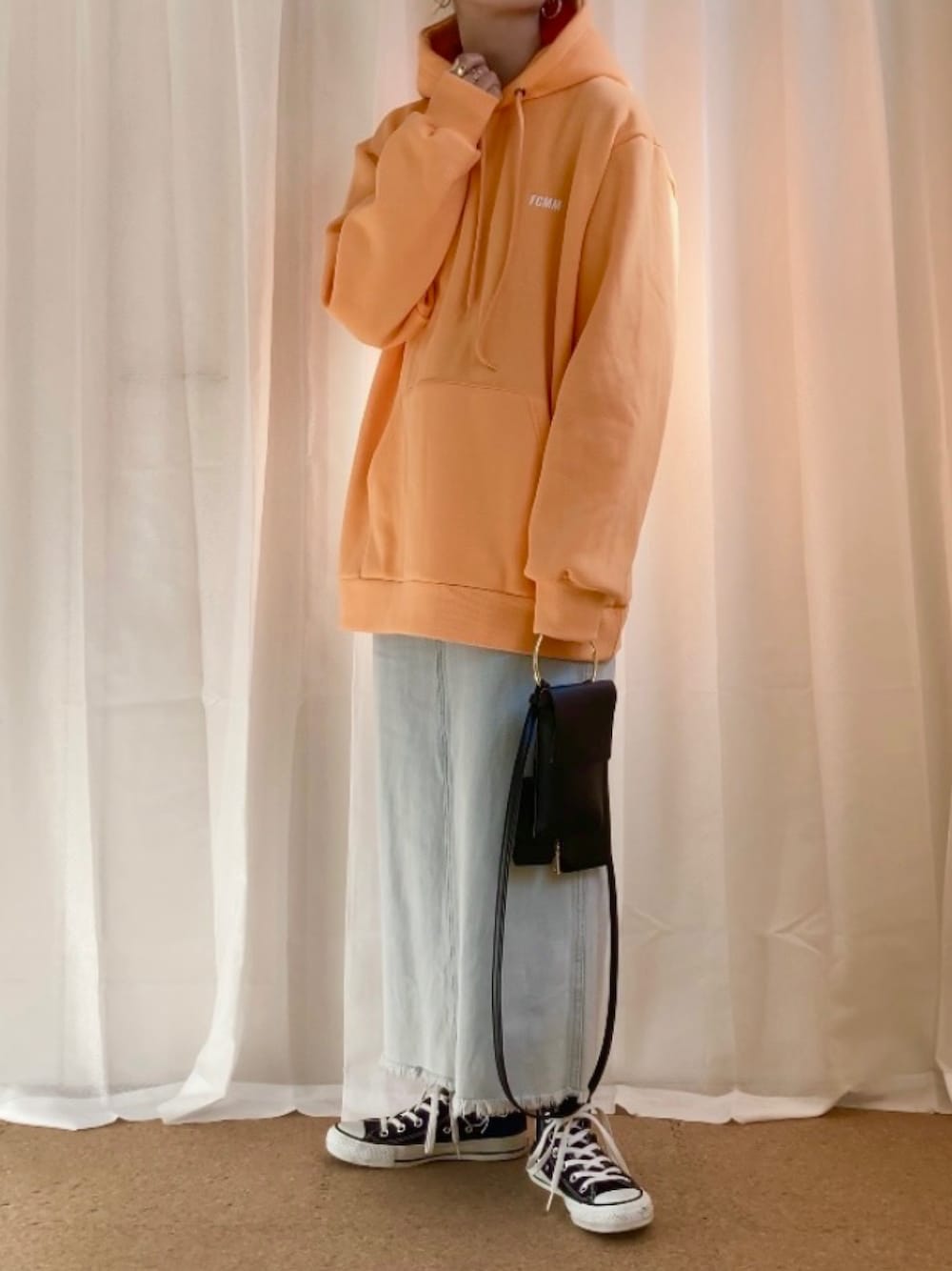 オレンジ系のパーカー、ブルー系のスカート、ブラック系のショルダーバッグを着用したレディースの春コーディネートの1枚目の写真