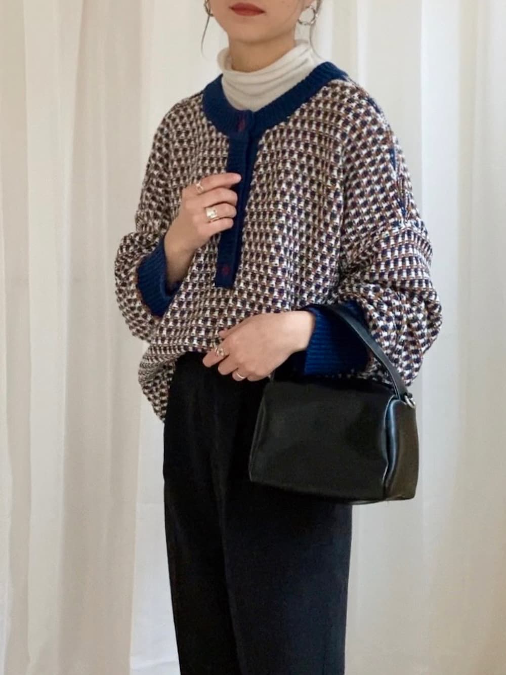 ブルー系のニット/セーター、ブラック系のスラックス、ブラック系のショルダーバッグを着用したレディースの冬コーディネートの1枚目の写真