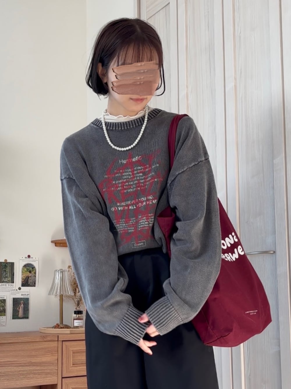 ブラック系のニット/セーター、ブラック系のチノパンツ、レッド系のトートバッグを着用したレディースの冬コーディネートの1枚目の写真