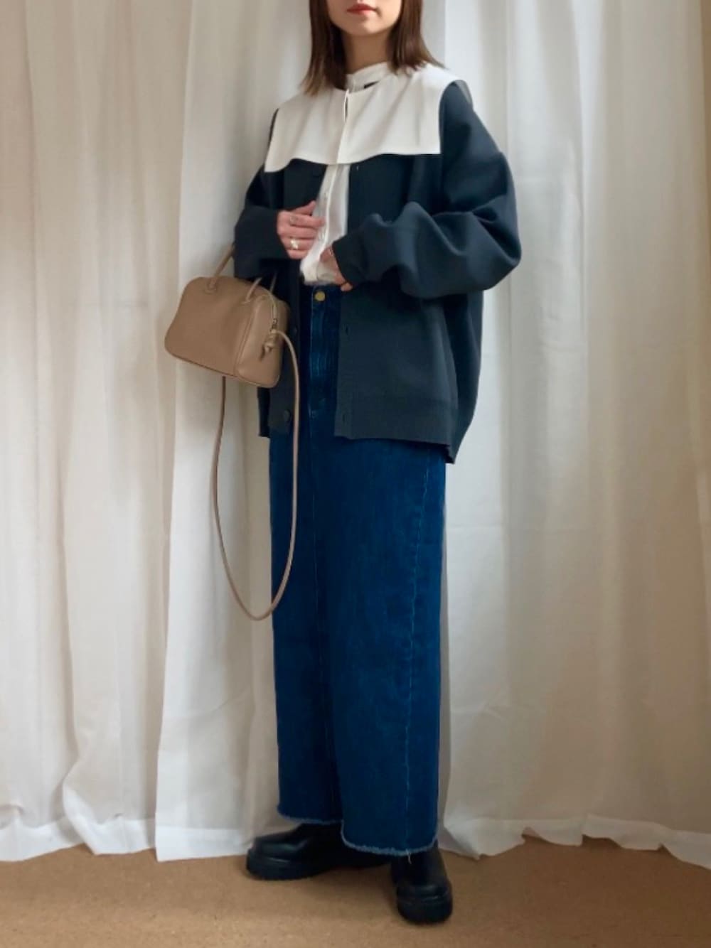 グレー系のカーディガン/ボレロ、ホワイト系のシャツ/ブラウス、ブルー系のデニムスカートを着用したレディースの冬コーディネートの1枚目の写真