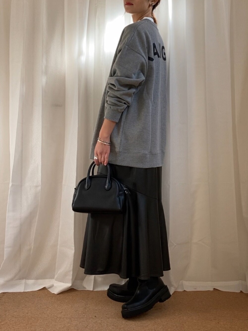 グレー系のスウェット、ブラック系のボストンバッグ、ブラック系のブーツを着用したレディースの冬コーディネートの1枚目の写真