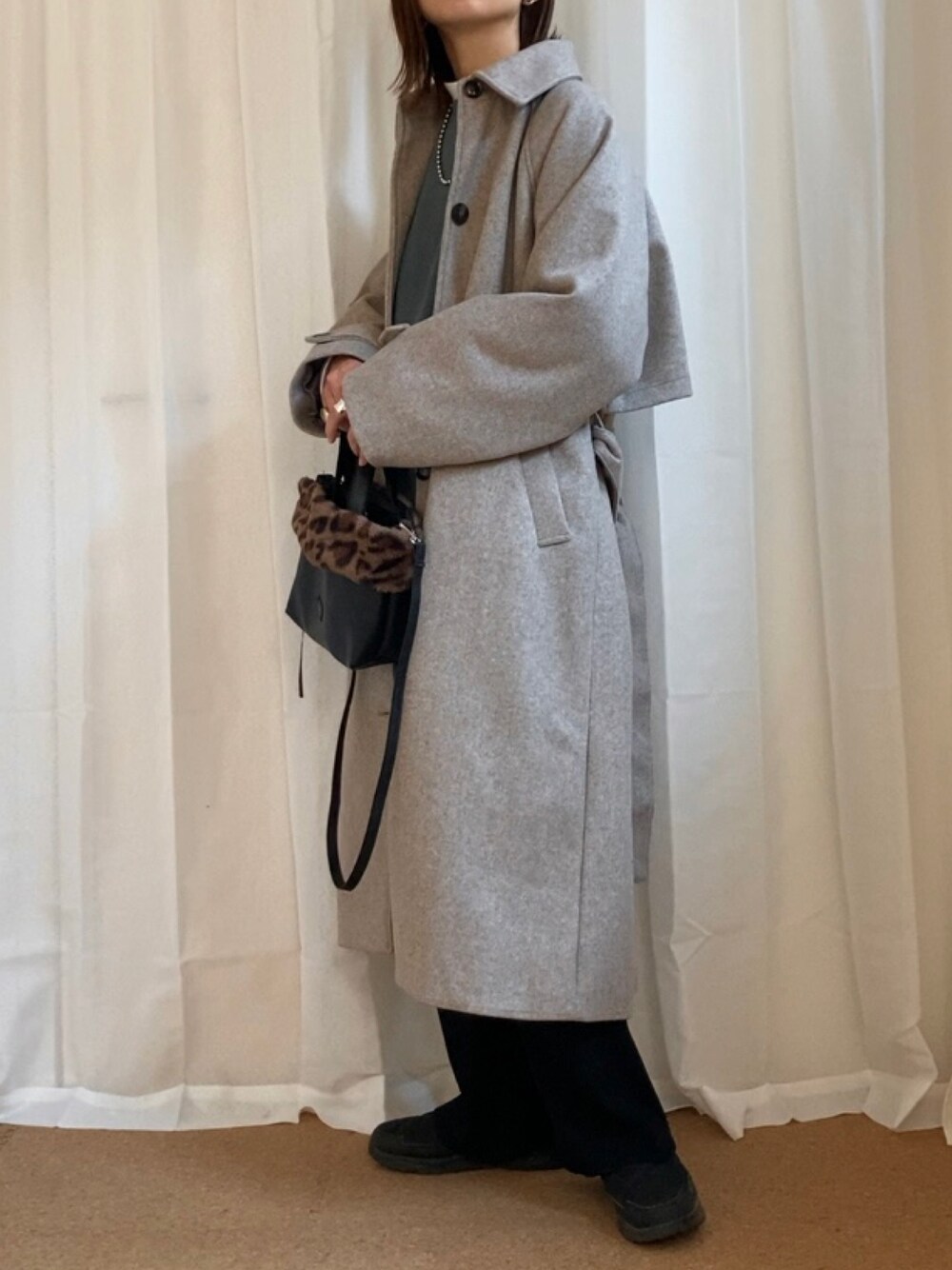 ベージュ系のステンカラーコート、ブルー系のスウェット、ブラック系のその他パンツを着用したレディースの秋コーディネートの1枚目の写真