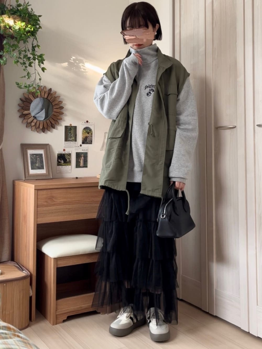 グレー系のスウェット、グリーン系のベスト、ブラック系のスカートを着用したレディースの春コーディネートの1枚目の写真