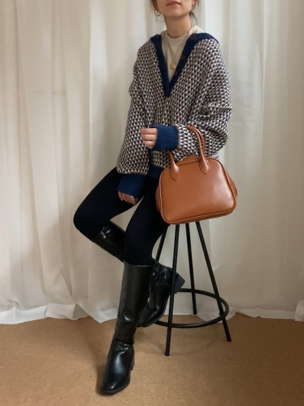 ブルー系のニット/セーター、イエロー系のボストンバッグ、ブラック系のブーツを着用したレディースの冬コーディネートの1枚目の写真