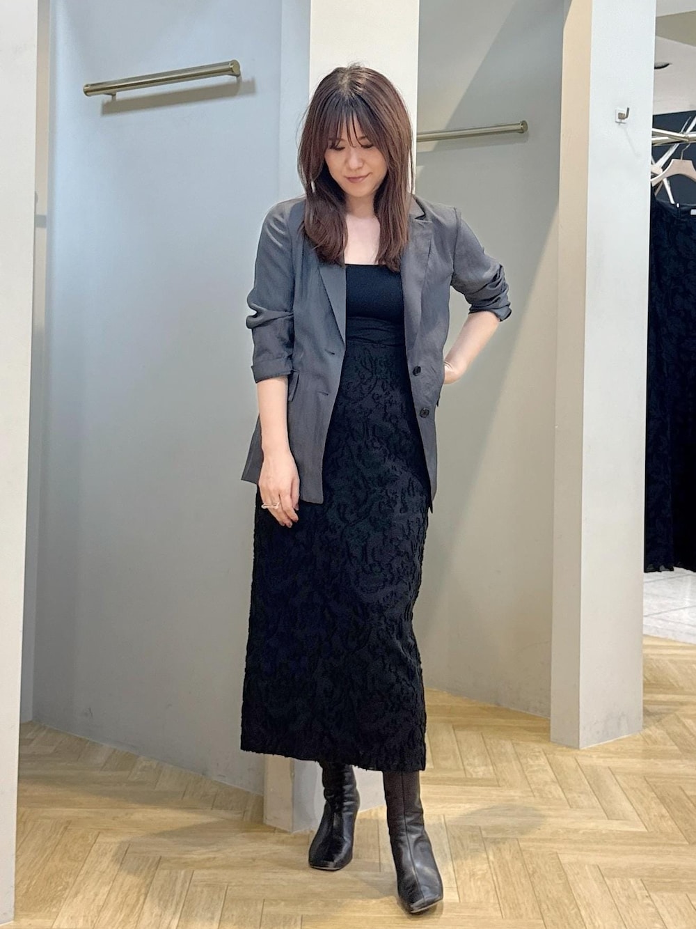グレー系のテーラードジャケット、ブラック系のスカートを着用したレディースの秋コーディネートの1枚目の写真