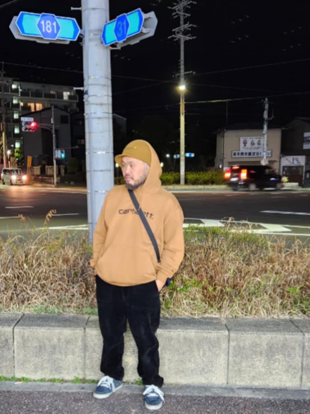 ブルー系のスニーカー、ブラック系のスラックス、ブラウン系のパーカーを着用したメンズの春コーディネートの1枚目の写真