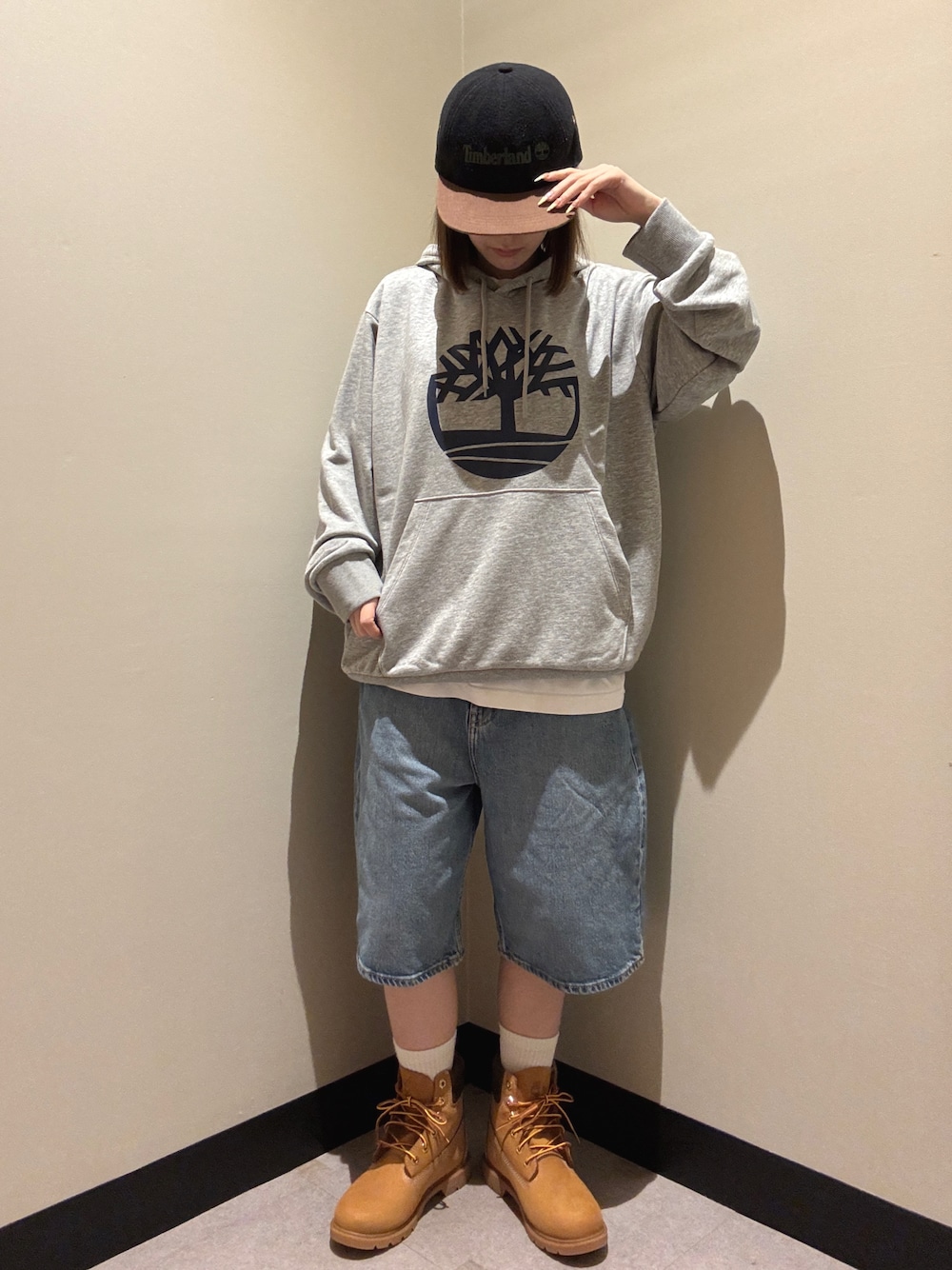 グレー系のパーカー、ブルー系のデニムパンツ、ベージュ系のブーツを着用したレディースの秋コーディネートの1枚目の写真