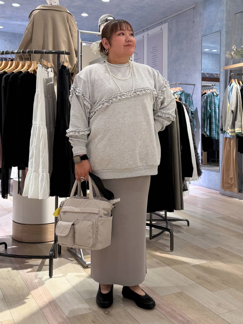 グレー系のスカート、ホワイト系のトートバッグ、ブラック系のパンプスを着用したレディースの冬コーディネートの1枚目の写真