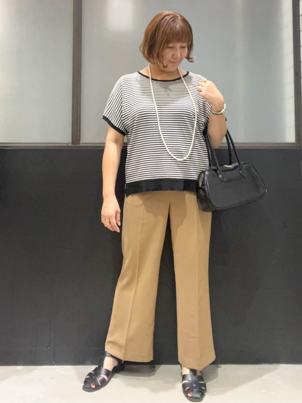 ブラック系のニット/セーター、イエロー系のその他パンツ、ブラック系のボストンバッグを着用したレディースの夏コーディネートの1枚目の写真