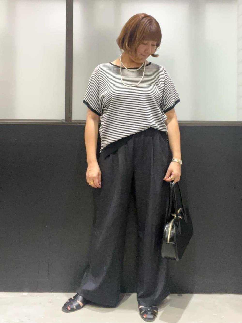 ブラック系のニット/セーター、ブラック系のその他パンツ、ブラック系のボストンバッグを着用したレディースの夏コーディネートの1枚目の写真