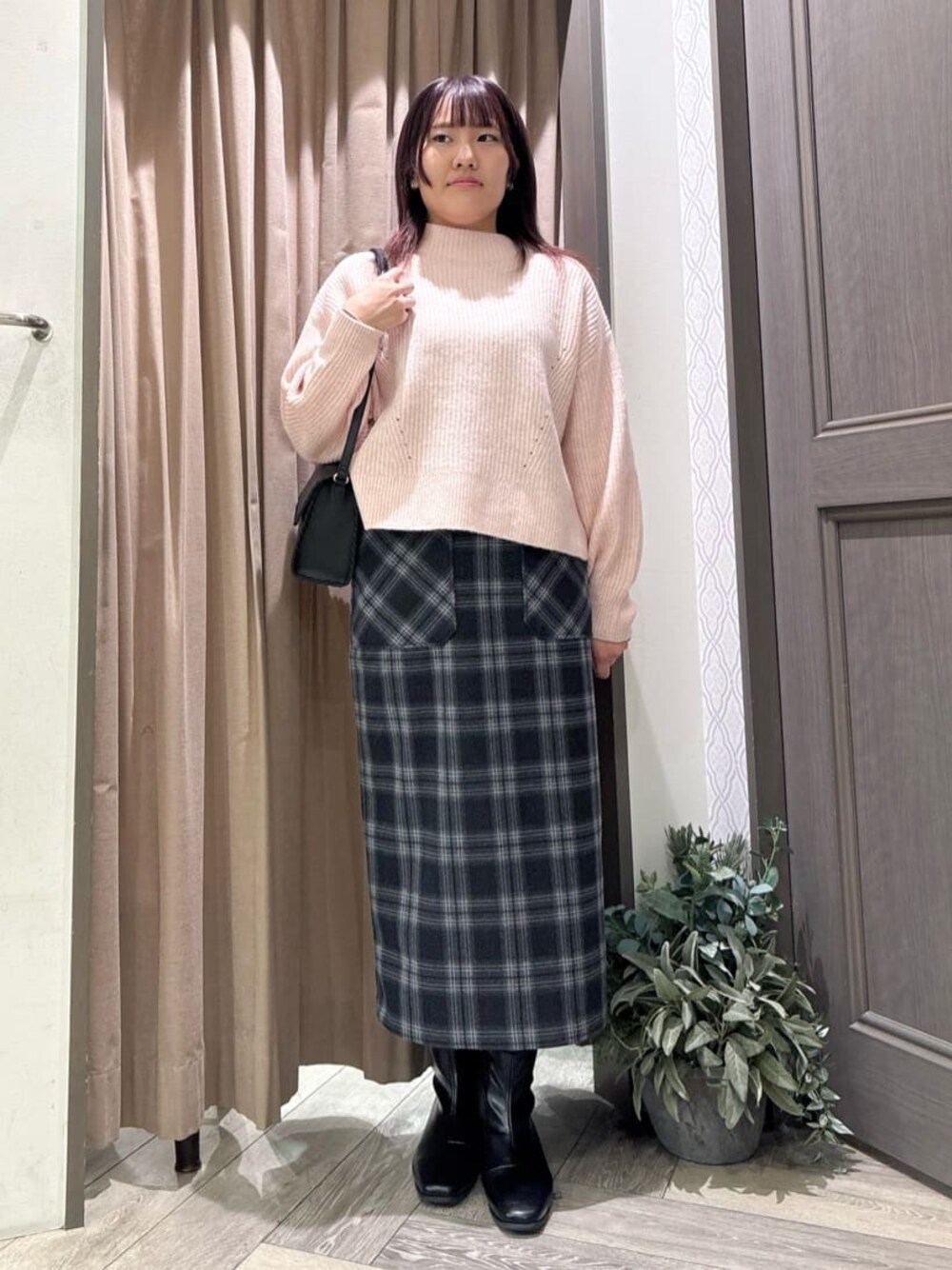 ピンク系のニット/セーター、ブルー系のスカート、ブラック系のショルダーバッグを着用したレディースの冬コーディネートの1枚目の写真