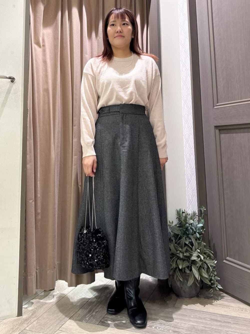ピンク系のニット/セーター、グレー系のスカート、ブラック系のショルダーバッグを着用したレディースの秋コーディネートの1枚目の写真