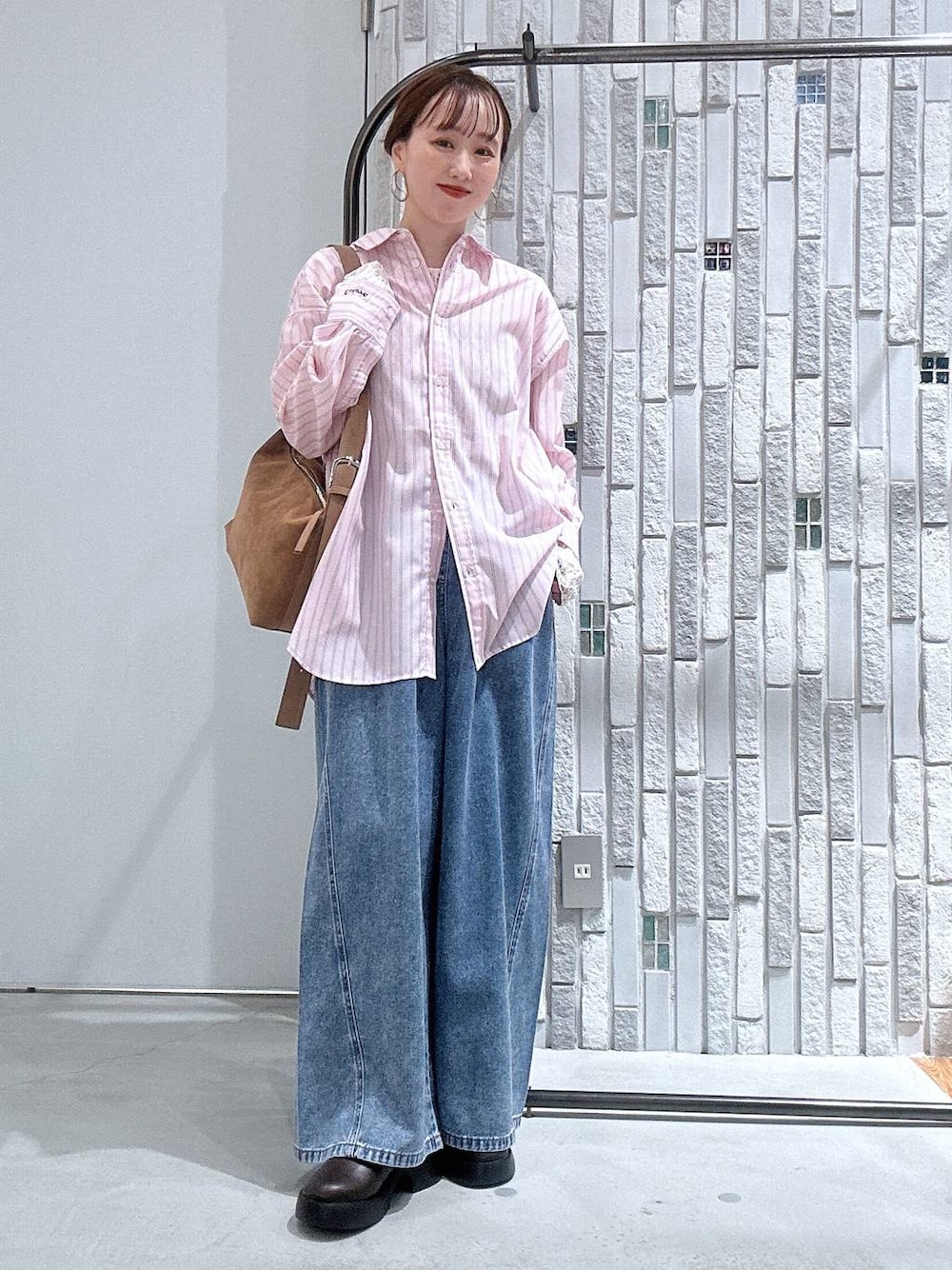 ブラウン系のショルダーバッグ、ブラウン系のサンダル、ブルー系のデニムパンツを着用したレディースの冬コーディネートの1枚目の写真