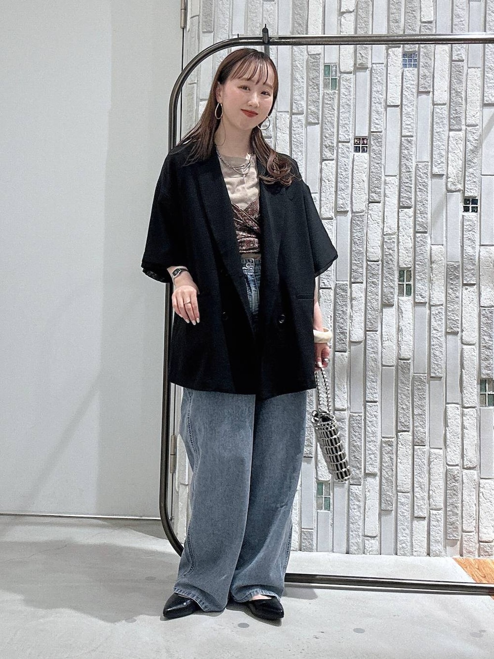 ブルー系のデニムパンツ、ブラック系のテーラードジャケット、シルバー系のショルダーバッグを着用したレディースの春コーディネートの1枚目の写真