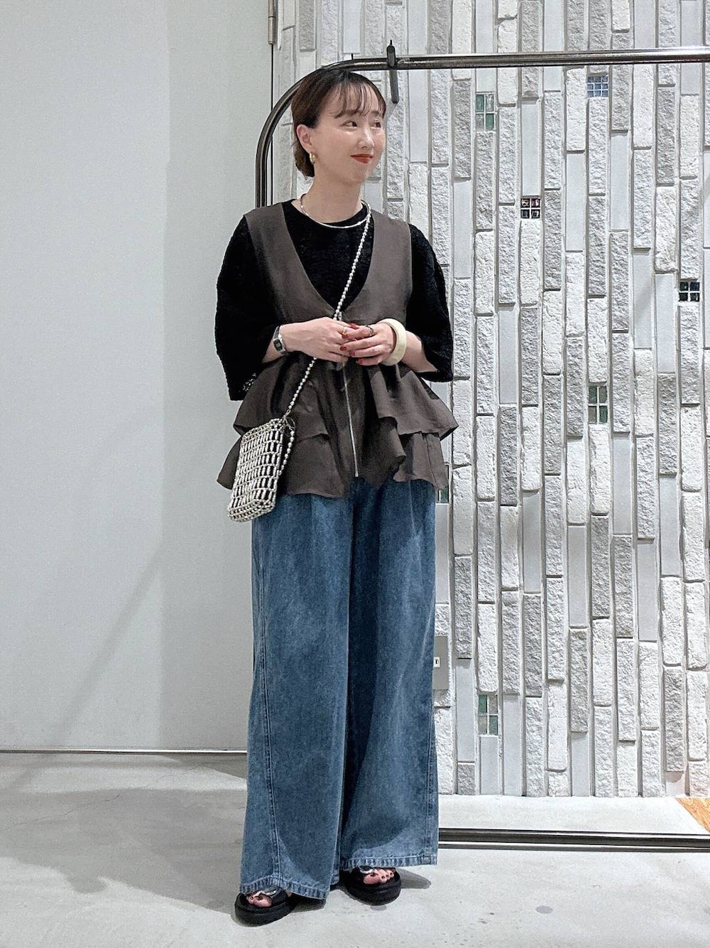 ブルー系のデニムパンツ、ブラック系のサンダル、シルバー系のショルダーバッグを着用したレディースの夏コーディネートの1枚目の写真