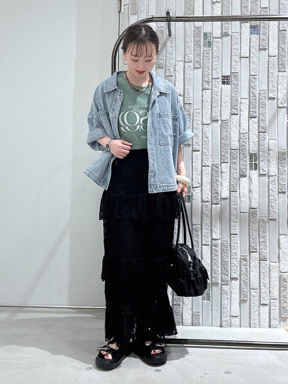 ブラック系のサンダル、ブルー系のシャツ/ブラウス、ブラック系のボストンバッグを着用したレディースの春コーディネートの1枚目の写真