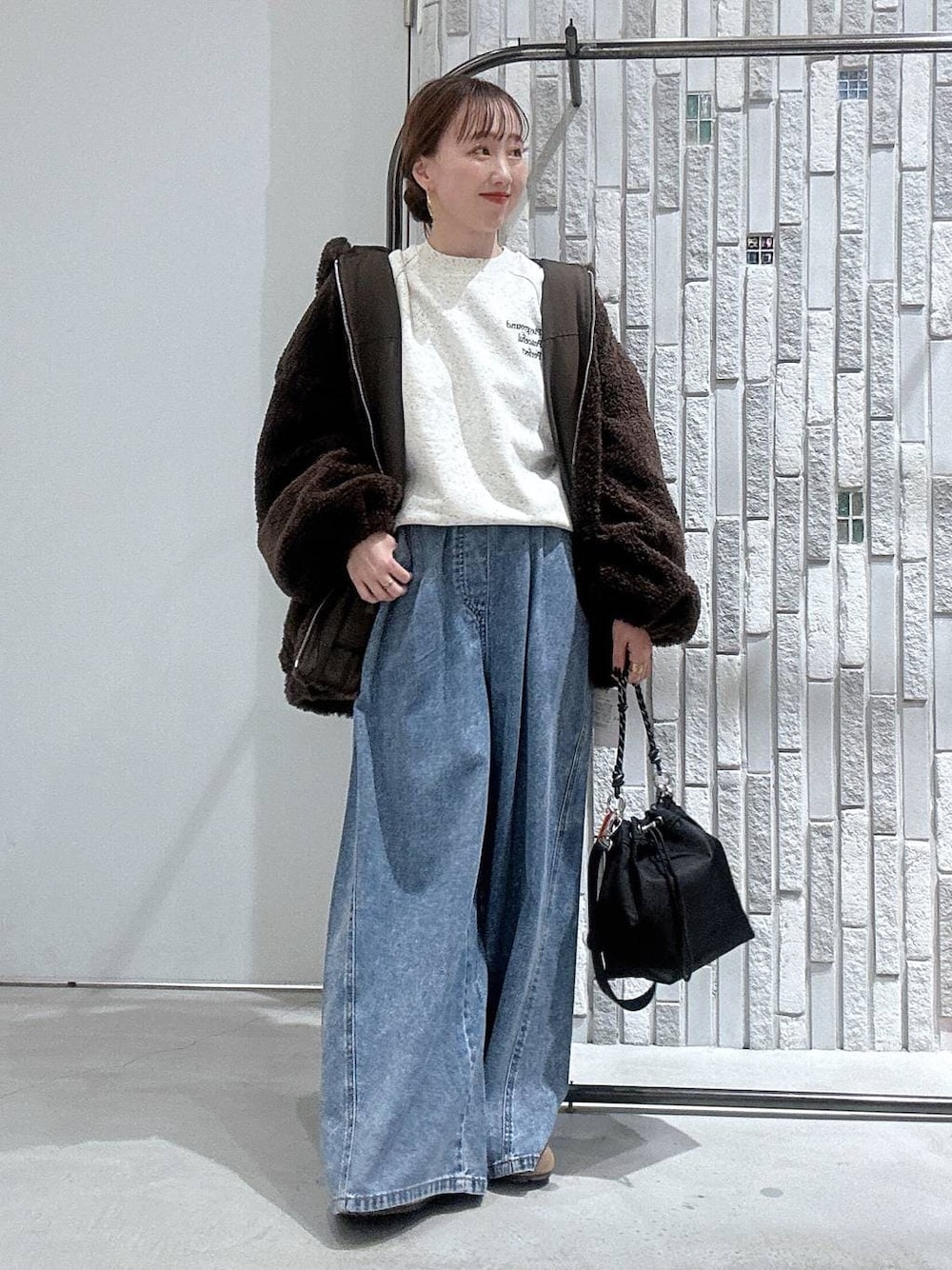 ブラック系のショルダーバッグ、ブルー系のデニムパンツ、ブラウン系のブルゾンを着用したレディースの冬コーディネートの1枚目の写真