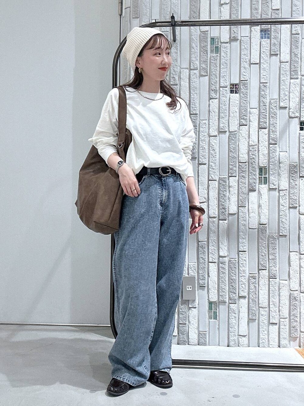 ブルー系のデニムパンツ、ブラウン系のショルダーバッグ、ホワイト系のTシャツ/カットソーを着用したレディースの春コーディネートの1枚目の写真
