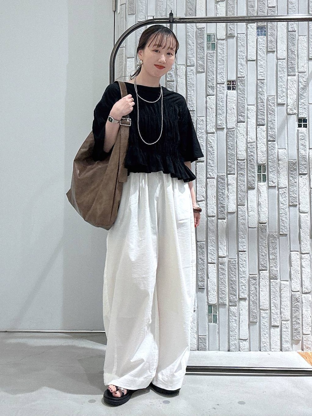 ブラック系のサンダル、ホワイト系のその他パンツ、ブラウン系のショルダーバッグを着用したレディースの春コーディネートの1枚目の写真